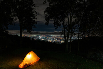 Night lights city view from the mountain while camping. The city lights twinkled like stars in the dark sky, The night was clear and calm. City background