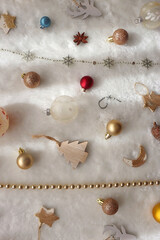 Various colorful Christmas oranments and white faux fur blanket. Top view.