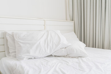 White pillow on wrinkle bed sheet in hotel room in the morning , soft focus,  concept of bedding,...