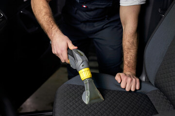 Car seat vacuum, car detailing and cleaning of interior seats at luxury modern cars. Close-up...