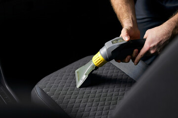 Car seat vacuum, car detailing and cleaning of interior seats at luxury modern cars. Close-up...