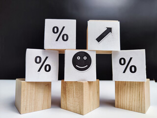 Wooden cubes in a column and a row with white signs with a smiley sign, an arrow, a percentage. The concept of positivism. Positive thinking leads to the achievement of results and profits