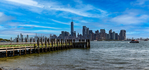 Beautiful panoramic photograph of a pier with the New York skyline in the background, specifically...