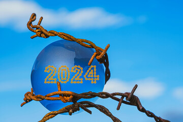 The concept of symbolism. On a blue sky is a glass globe with 2024 Happy New Year made from golden...