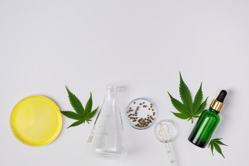 Cannabis CBD oil and hemp leaves with laboratory glass top view. Laboratory glassware and cannabis...