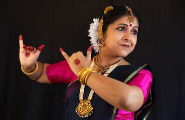 Woman Bharatanatyam Classical dancer perform Indian Classical dance on black background in close up.
