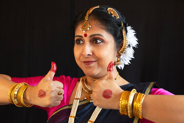 Female Indian classical dancer in traditional Bharatanatyam costume demonstrate dance mudra on dark background