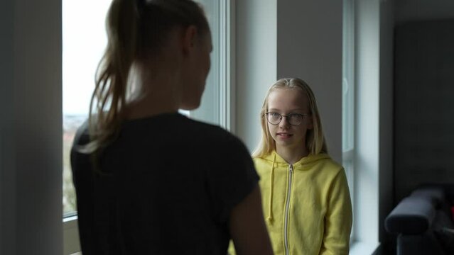 Close-up camera view of teen girl explaining to her mother what happened at school. Mother and daughter conversation. Young blond schoolgirl with glasses.