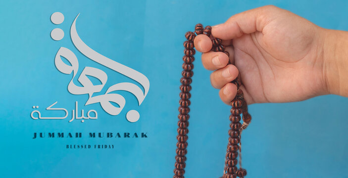 Jummah Mubarak blessed happy Friday Arabic calligraphy, Selective focus image hand of Muslim woman holding prayer beads.