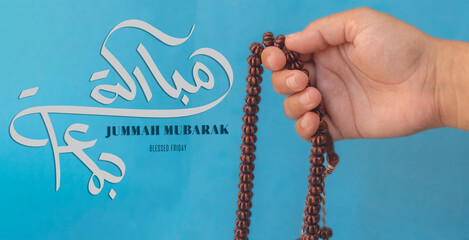 Jummah Mubarak blessed happy Friday Arabic calligraphy, Selective focus image hand of Muslim woman holding prayer beads.