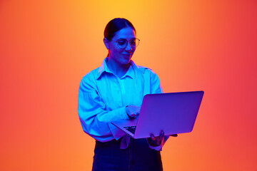 Portrait of business lady holds laptop and working online, conducts briefing against gradient...
