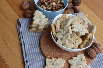 Walnut cookies in shape of a tree ina white bowl with dry walnuts on woooden table 