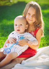 Two children baby brother and sister on green meadow