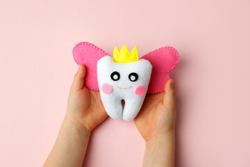 Felt tooth fairy pillow in kids hands on pink background with copy space for text. Handmade children's felt tooth fairy pillow. Stuffed toy crafts idea. Happy Tooth Fairy day card