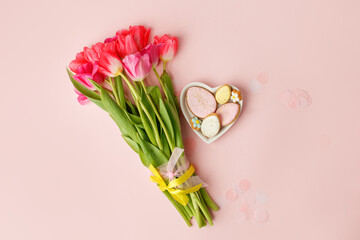 Happy Easter. Multi-colored pastel easter cookies gingerbread, seasonal flowers tulips on pink background. Easter concept, copy space, flyer, banner, coupon, greeting card, invitation