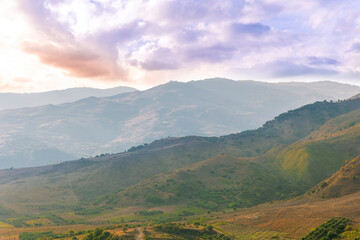 Naklejka premium scenic rustic landscape with green hills and farms in a mountain valley during colorful cloudy sunset