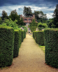 Pathway bordered by hedges in the sprawling gardens leading to Country estate house in the English...