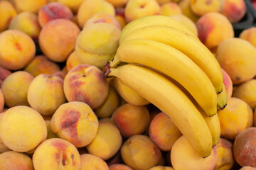 Branch of yellow ripe bananas and peaches.Tropical fruits on sale.