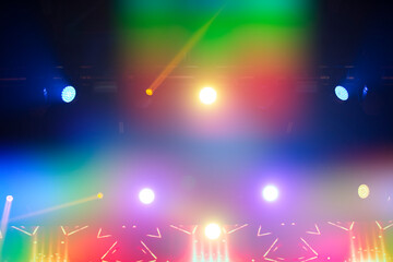 Bright festive multi-colored stage lighting with optical flare and rays from lighting lamps.