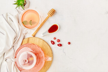 Glass teapot and cup of organic berry tea with honey - aesthetic table setting. Copy space