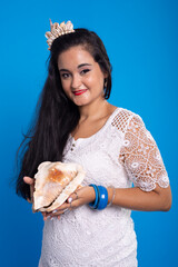 Beautiful young woman in white dress with shell tiara on her head holding a sea shell and looking...