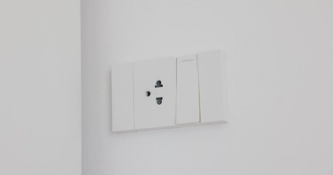 Man's hand Turn on, turn off light switch in office. white one electrical outlet and one light switch. Solution video 4K. Concept of technology, connection, power saving, energy saving.