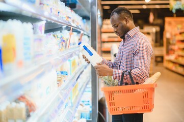 African man shopping at supermarket. Handsome guy holding shopping basket