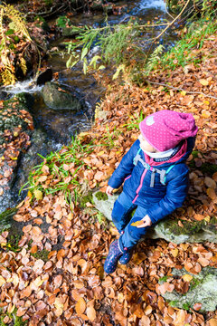 Kind am Bach im Wald beim Spielen