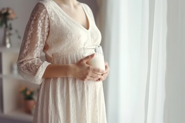 Close-up of a pregnant woman in a white dress, holding a glass of milk, focusing on a healthy diet.