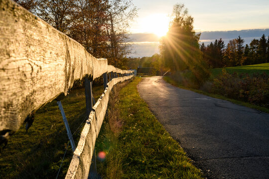 Landstra&szlig;e mit Holzzaun im Sonnenuntergang