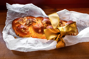 Traditional sweet braided Christmas pastry with almond and golden ribbon on paper.