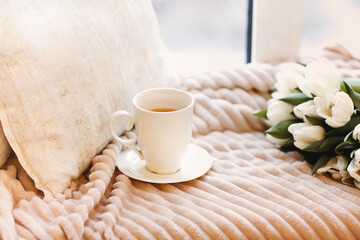 Tulips and cup of coffee on bed