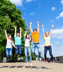 Group of smiling teenagers jumping outdoors