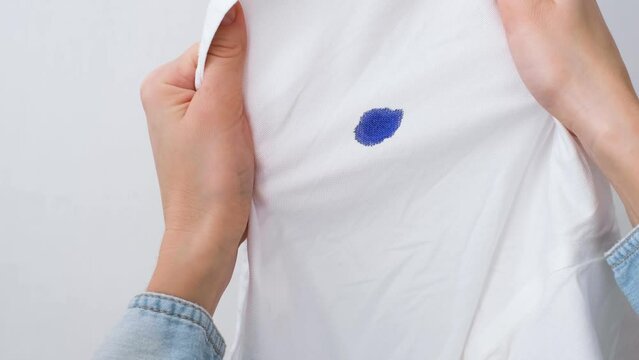 Unrecognizable woman holding spoiled white shirt. Dirty ink stain on a white clothes. daily life stain concept. High quality 4k footage