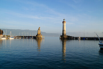 	
sunlit harbour and beacon of Lindau on tranquil lake Constance (lake Bodensee) with the Alps in...