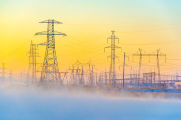 Powerful power lines stretching across a foggy river. Mysterious winter fog creates an unearthly...
