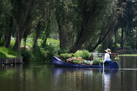 A Mexican woman paddles her canoe boat selling flowers and plants to tourists on a canal in Xochimilco, Mexico City