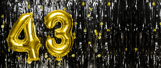Gold foil balloon number number 43 on a background of black tinsel decoration. Birthday card,...