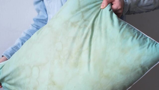Female hands change a pillowcase from dirty saliva stains on a pillow for longterm use cleaning 

