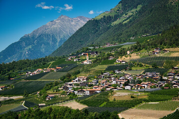 Panoramablick über ein Tal in Südtirol mit kleinen Ortschaften und Bergen im Hintergrund - obrazy, fototapety, plakaty