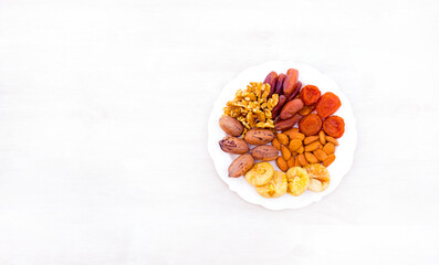 Vintage white plate with dried fruits for happy
Tu Bishvat.
Healthy natural food with lots of minerals and vitamins. On a white background wooden texture. from above top View. with free space for text