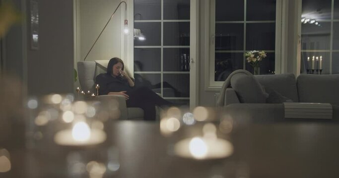 Woman crying at home with napkin tissue, candlelight xmas atmosphere, night