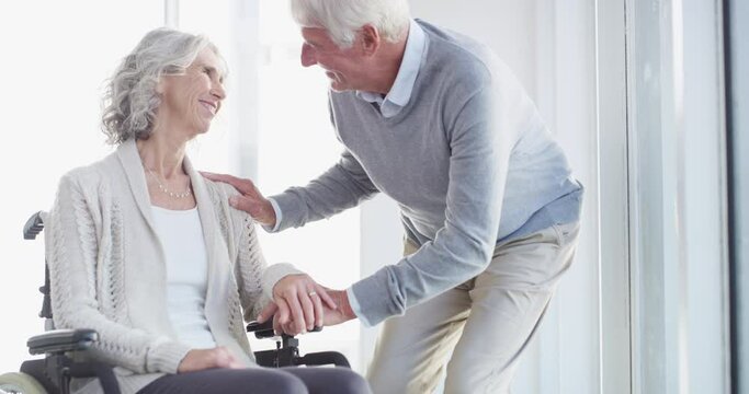 Wheelchair, love and senior couple in home for care, medical support and helping in living room. Marriage, retirement and happy man and woman talking for bonding, relationship and relax together