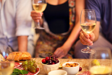 Hands of a group of people cheering with white wine