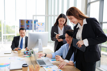 Asian businessperson colleagues discussing with computer in office.