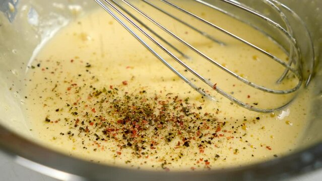 Cooking homemade mayonnaise sause adding black red ground pepper to metal bowl on kitchen. Cooking sauce for salad, meat dishes. Dressing for different dishes. Culinary, cuisine concept.