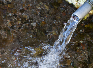 Water emerging from a pipe. Image Water scarcity and importance of fresh clean water in the environment.