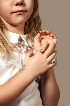 Jewellery concept. Crop image of cover girl child model advertising jewelry showing hand with ring on finger, poses gesture hands. Perfect kid little lady close up, studio shot. Copy ad text space