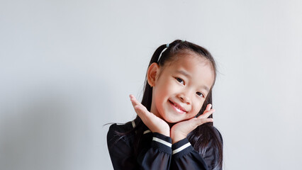 Closeup happy cute little Asian girl in black dress smiling over gray background