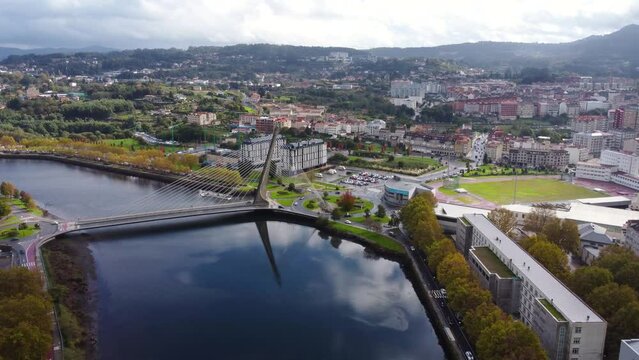 Cinematic aerial perspective of Pontevedra city. Famous travel destination in Galicia. River Lerez and Puente de Los Tirantes. Drone forward descending